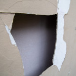 Broken ACM fibro sheet on wall with peeling paint on non-residential building