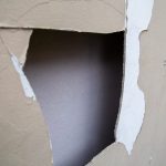 Broken ACM fibro sheet on wall with peeling paint on non-residential building